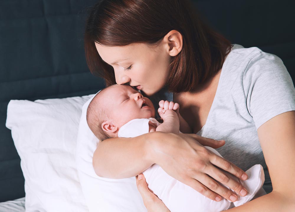 mom kissing newborn