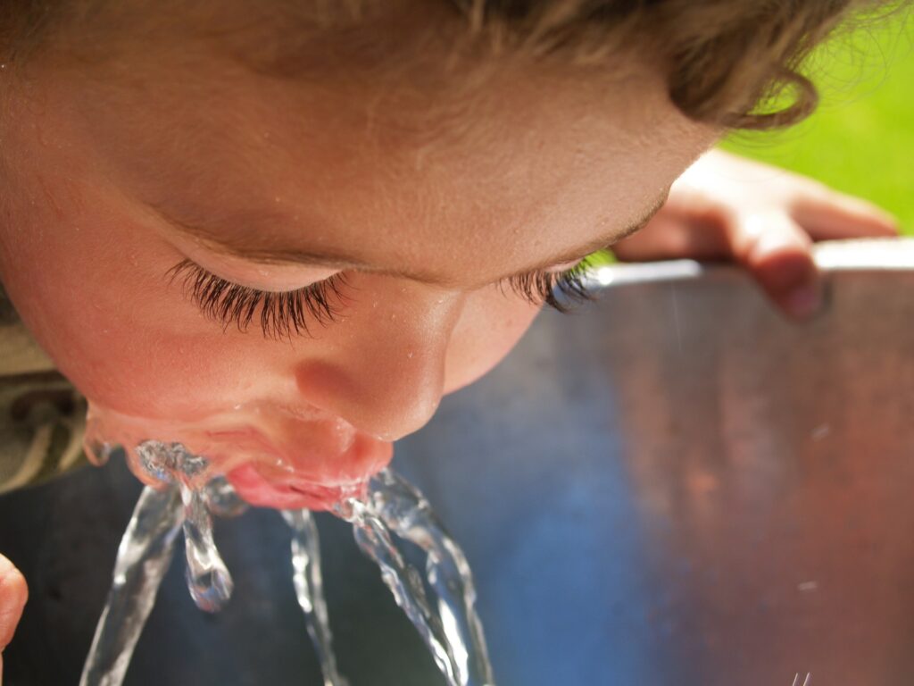 Child drinks from water fountain.