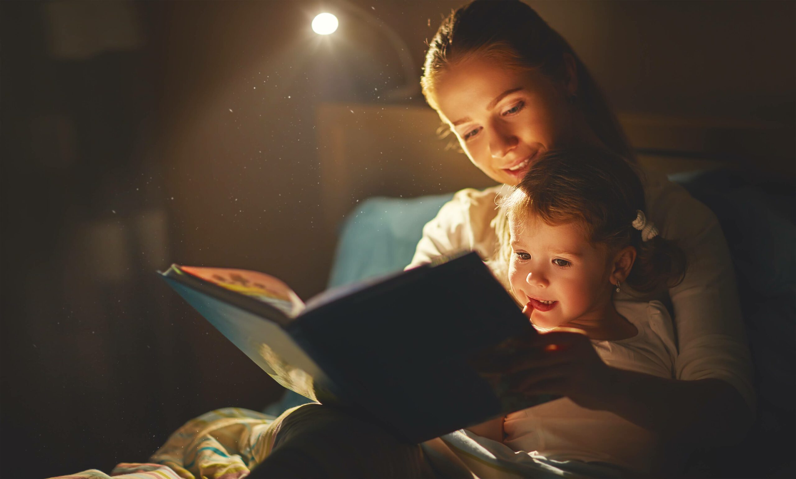 A mother reads a book to their child as part of a bedtime routine.