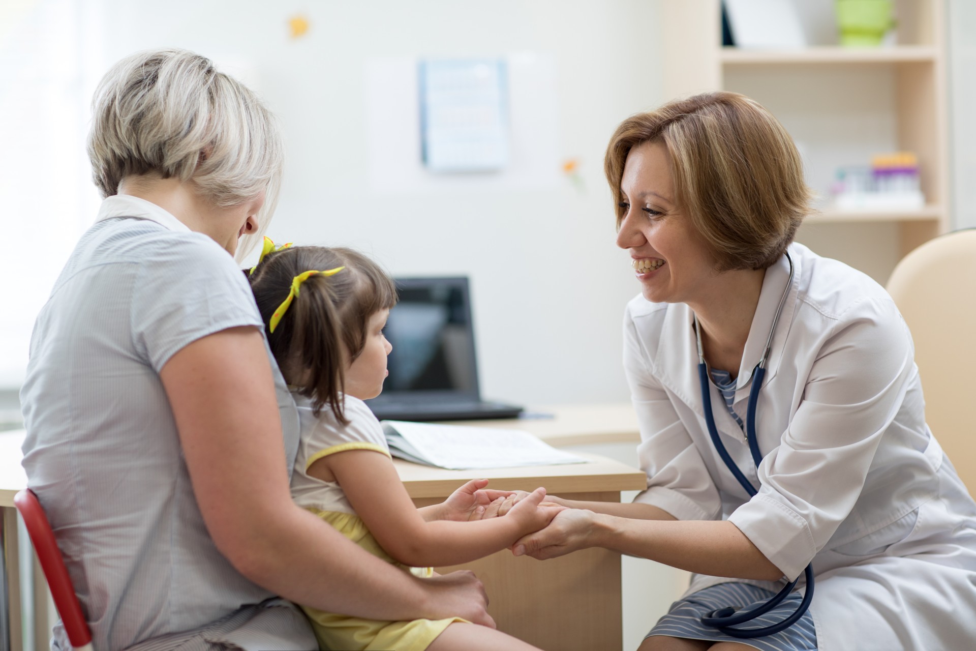 Mother and child sit with a pediatrician at their first doctor's visit.