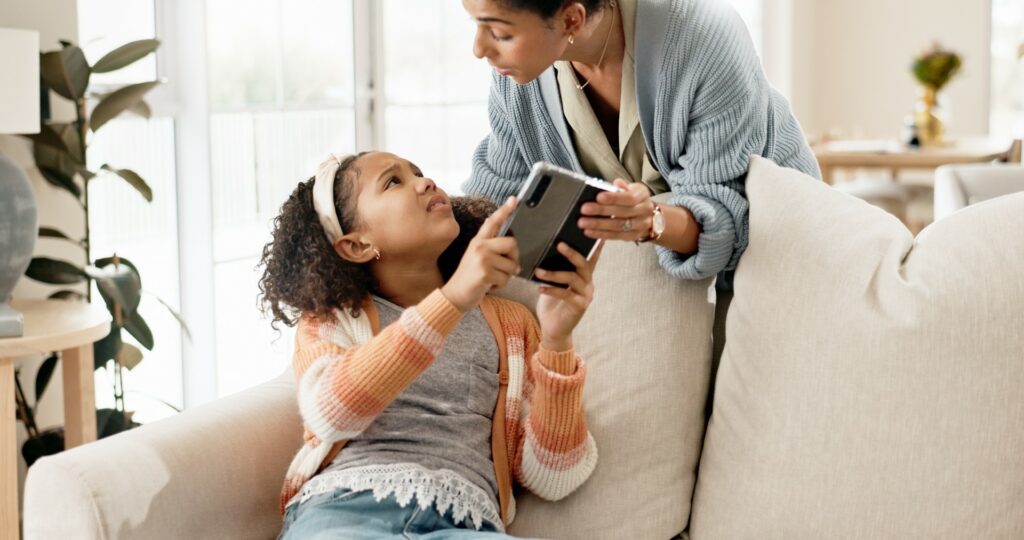 Mother takes an electronic device from her daughter.