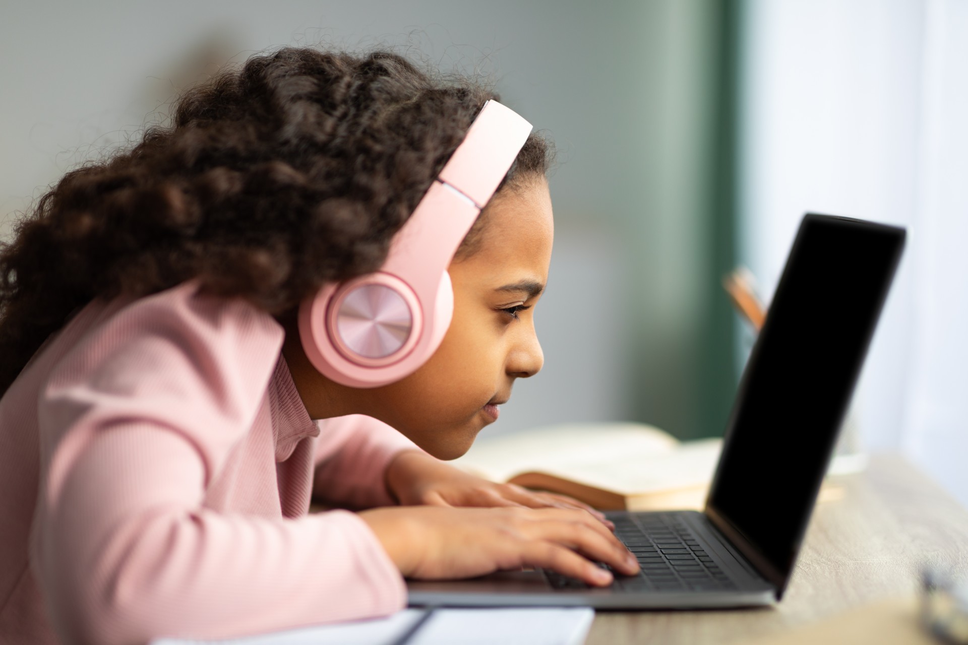 Young girl squints at her laptop screen, potentially struggling with vision problems.