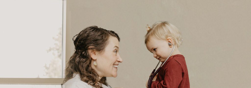 A joyful interaction between a mother and her child, both smiling, in a softly lit room with neutral tones.