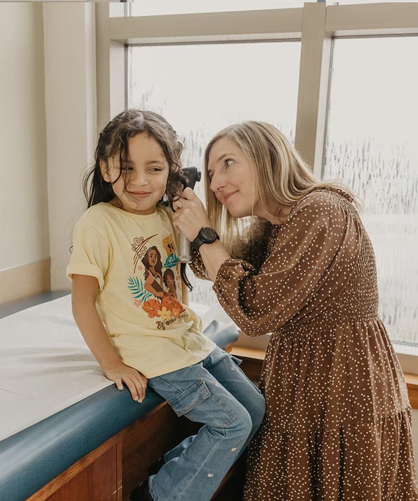 A healthcare professional examines a young child's ear in a bright, inviting environment, fostering a sense of care and trust.